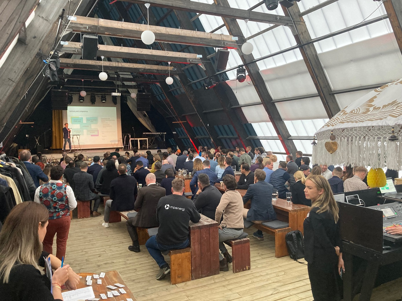 Sala ze sceną. Zgromadzenie ludzi przysłuchują się przem&oacute;wieniu