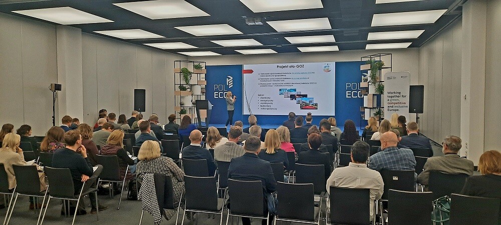 Ludzie siedzą na sali i patrzą się w telebim