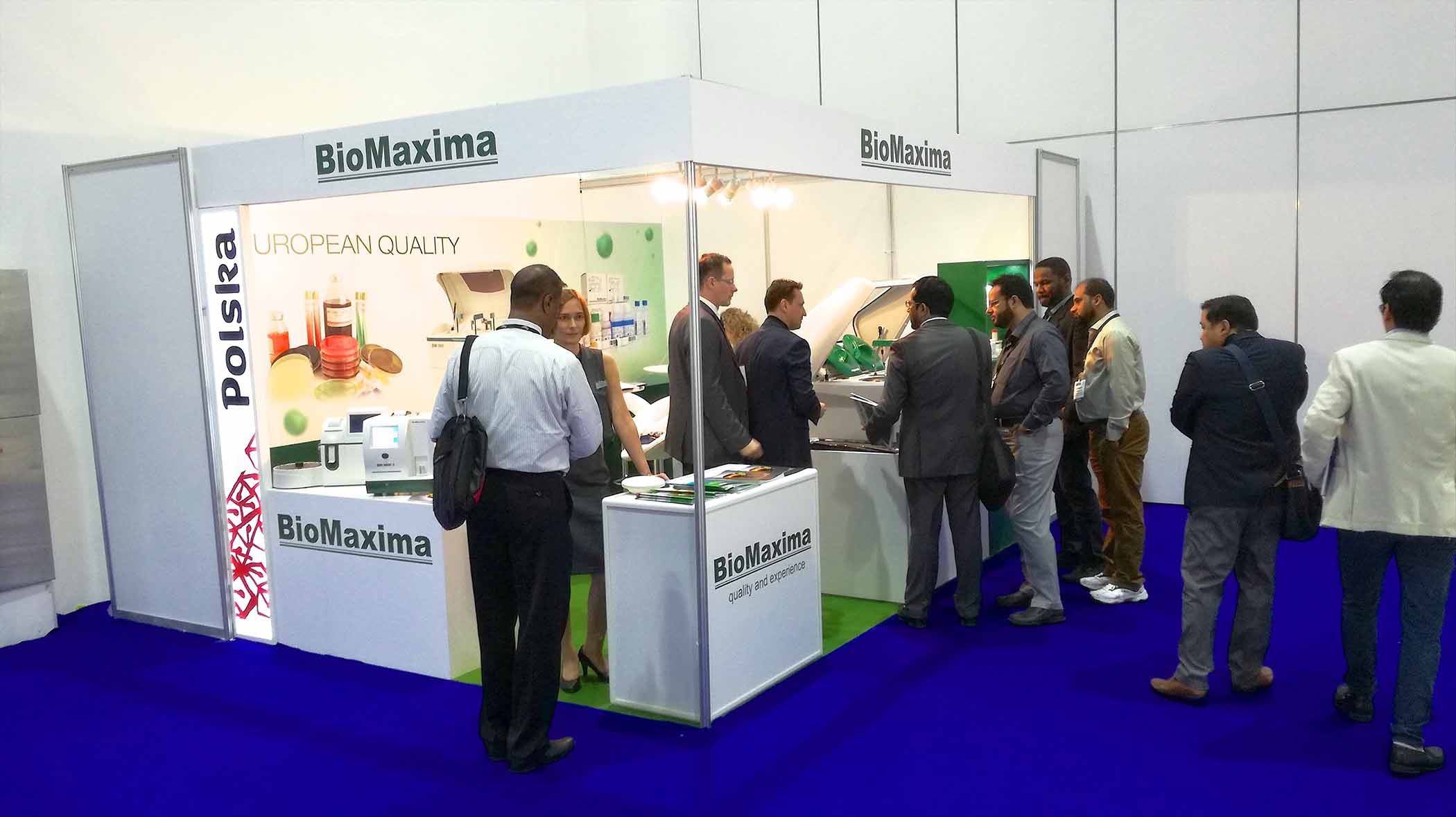 Zdjęcie soiska targowego z szyldem BioMaxima z stojącymi uczestnikami targ&oacute;w