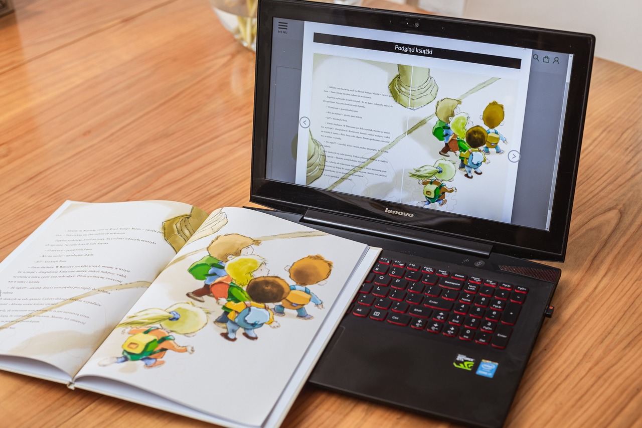 Otwarty laptop stoi na blacie, na laptopie znajduje się katalog