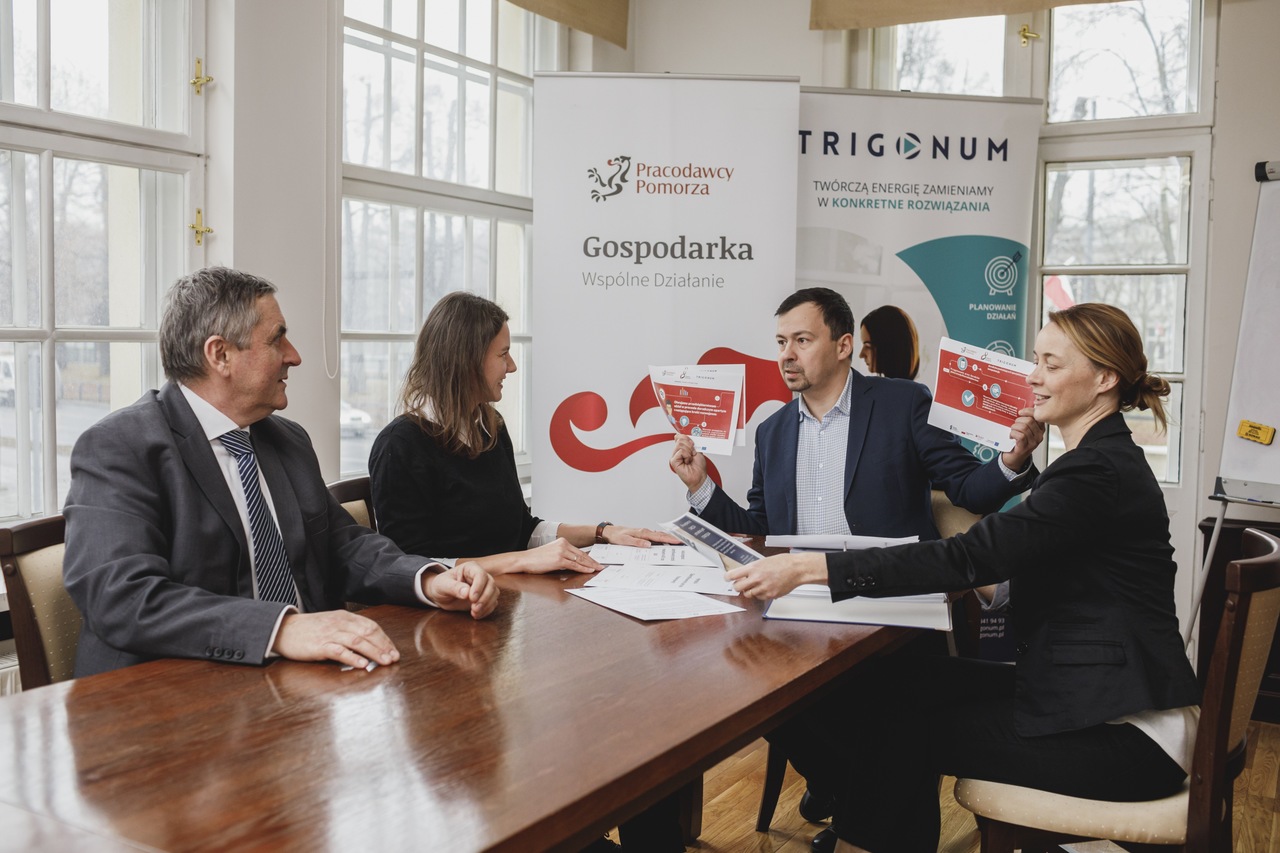 Grupa ludzi siedzi przy stole i rozmawia