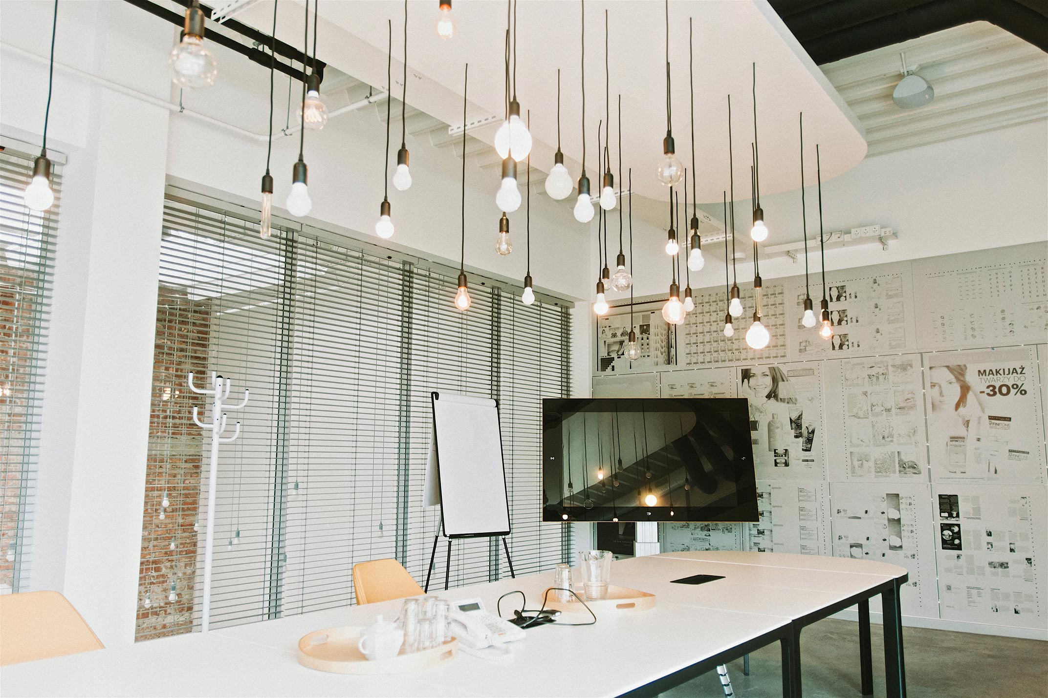 Widok wiszących żar&oacute;wek nad stołem, na kt&oacute;rym stoi komputer